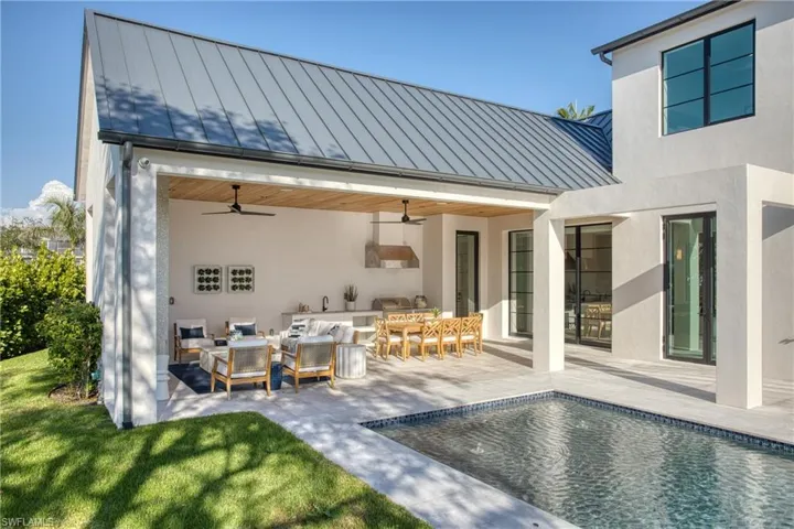 Back of house featuring ceiling fan, metal roof, an outdoor pool, a standing seam roof, and stucco siding
