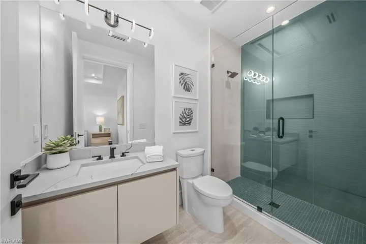 Bathroom featuring visible vents, toilet, a shower stall, and vanity