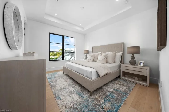 Bedroom featuring light wood-type flooring, a tray ceiling, baseboards, and recessed lighting