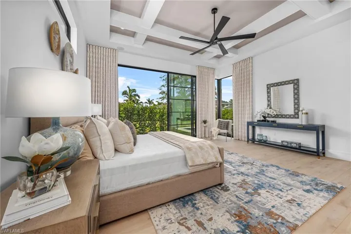 Bedroom with access to exterior, beam ceiling, coffered ceiling, and wood finished floors