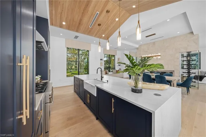 Kitchen featuring wooden ceiling, a spacious island, appliances with stainless steel finishes, decorative light fixtures, and a sink