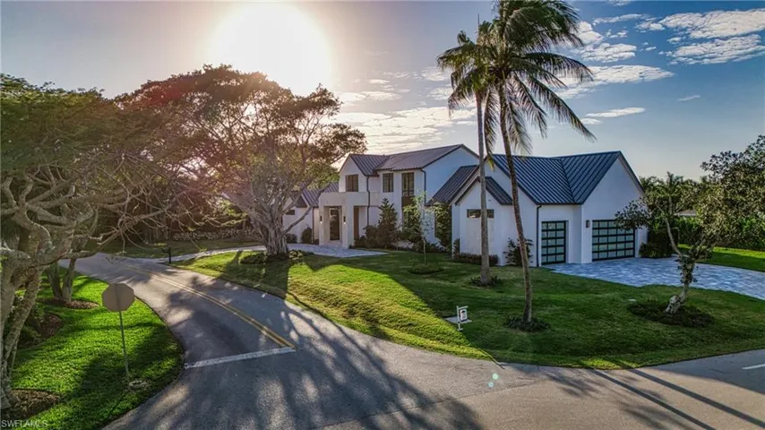 View of front of home featuring stucco siding, a front yard, a standing seam roof, metal roof, and driveway