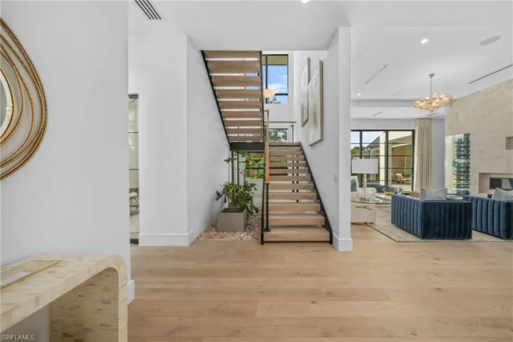 Staircase with a fireplace, recessed lighting, visible vents, an inviting chandelier, and wood finished floors