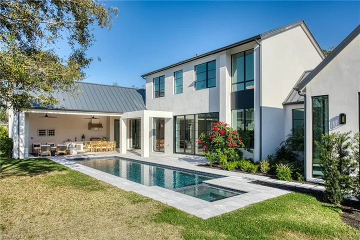 Back of house with a ceiling fan, metal roof, a standing seam roof, a yard, and stucco siding