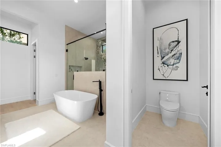 Bathroom with a stall shower, baseboards, toilet, tile patterned floors, and a freestanding bath