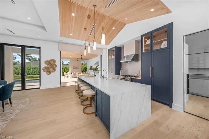 Kitchen featuring a spacious island, wood ceiling, blue cabinetry, glass insert cabinets, and pendant lighting