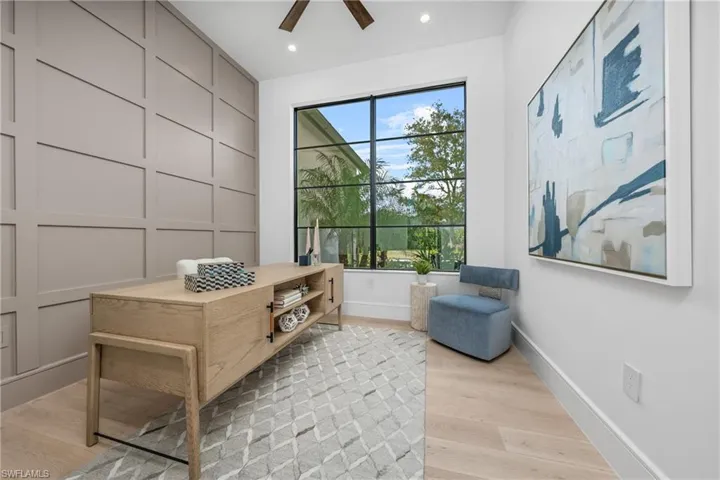 Living area with baseboards, plenty of natural light, a decorative wall, and light wood finished floors