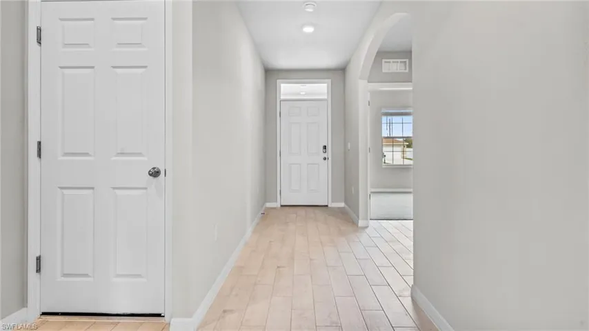 Hall with arched walkways and light wood-style floors