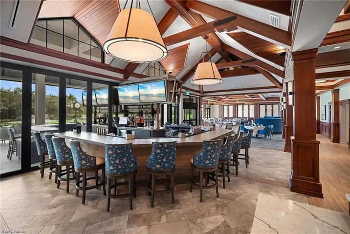 Bar area featuring beam ceiling, pendant lighting, healthy amount of natural light, high vaulted ceiling, and decorative columns