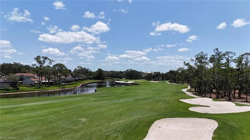 View of community with view of golf course, a water view, view of wooded area, and a yard