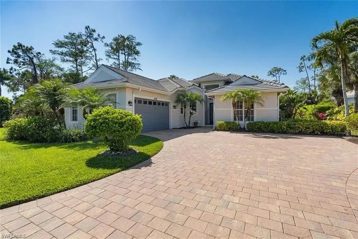 View of front of property featuring an attached garage, decorative driveway, stucco siding, and a front yard