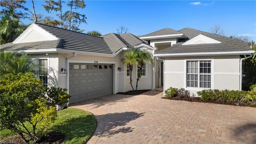 Ranch-style house with stucco siding, a garage, decorative driveway, and a tiled roof
