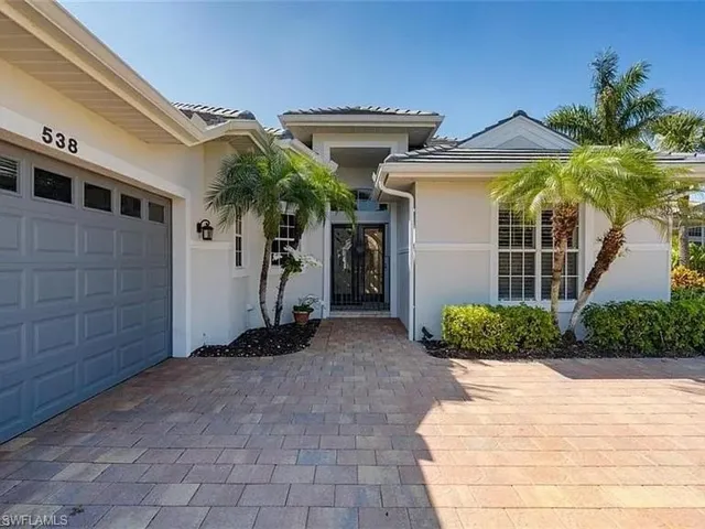 Doorway to property featuring stucco siding, driveway, a garage, and french doors