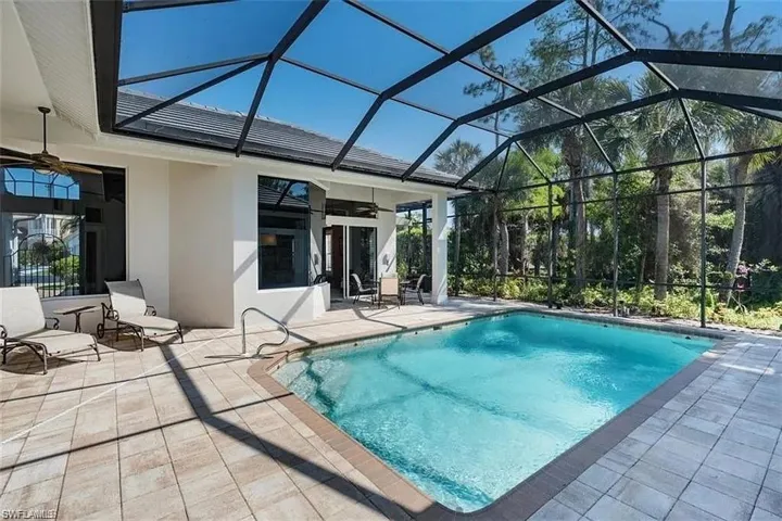 Outdoor pool featuring a sunroom, a patio, and glass enclosure