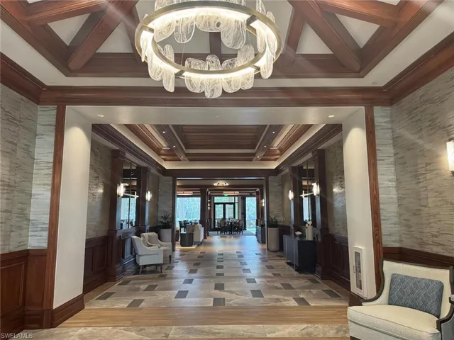 Building lobby with wainscoting, coffered ceiling, beam ceiling, crown molding, and a decorative wall