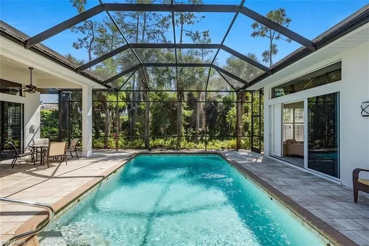 Outdoor pool featuring a patio, a sunroom, and glass enclosure