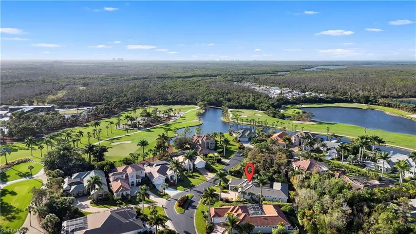 Aerial view of property's location featuring a golf course, a nearby body of water, and nearby suburban area