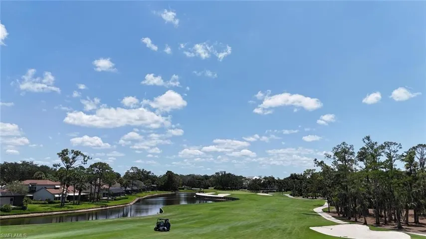 Surrounding community featuring golf course view, a lawn, a water view, and view of wooded area
