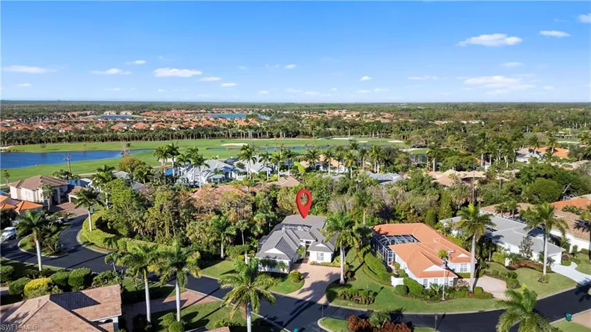 Aerial view of property and surrounding area featuring nearby suburban area, a nearby body of water, and a local golf course