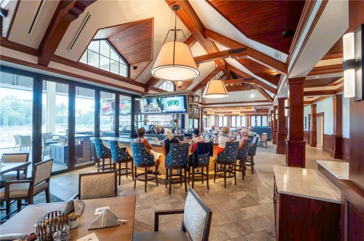 Dining room with high vaulted ceiling, beam ceiling, stone tile floors, and wainscoting