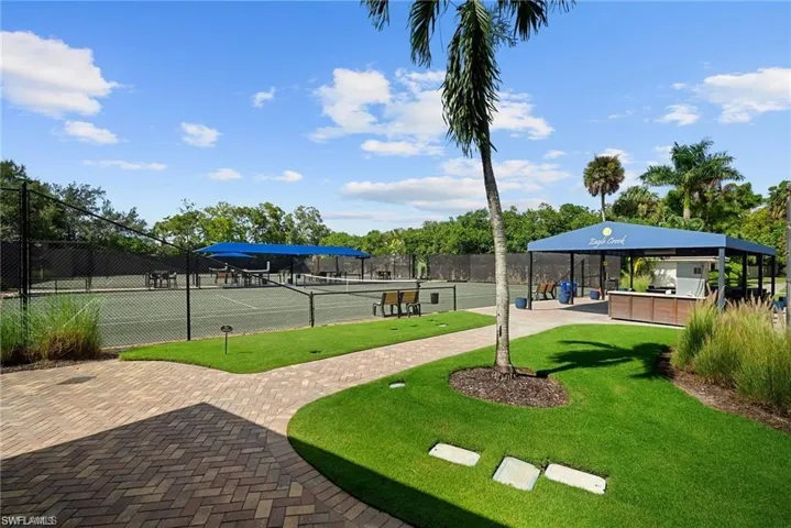 View of property's community with a tennis court and a patio