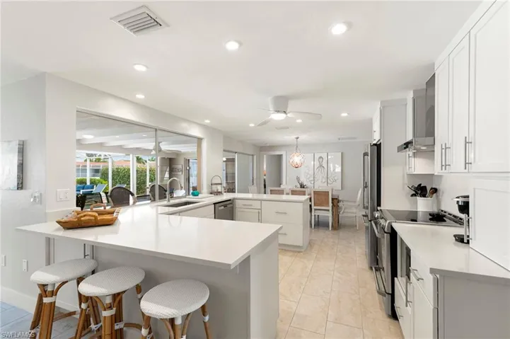 Kitchen featuring stainless steel appliances, sink, kitchen peninsula, ceiling fan, and a breakfast bar