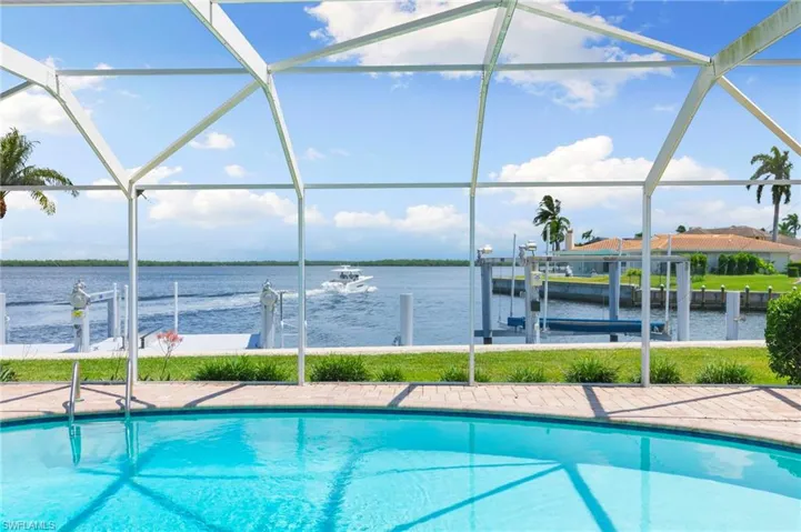 View of pool featuring a water view, glass enclosure, and a dock