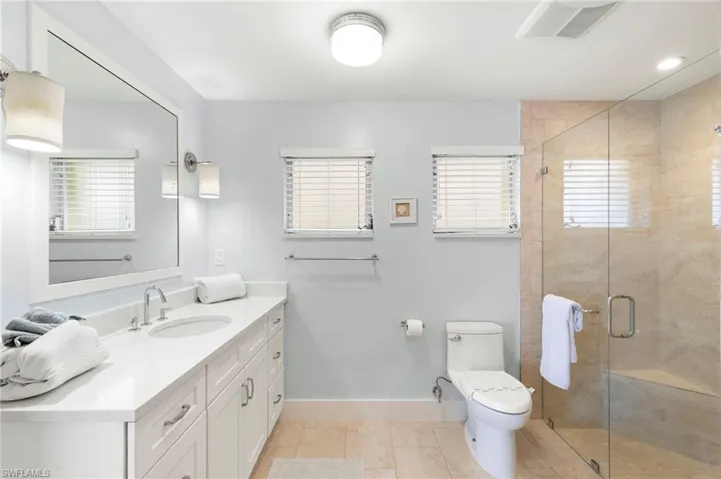 Bathroom with vanity, toilet, a shower with shower door, and tile patterned floors
