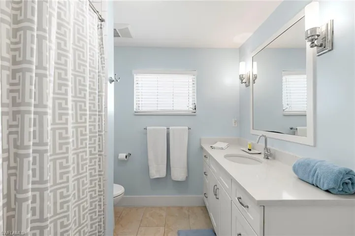 Bathroom featuring tile patterned flooring, vanity, toilet, and curtained shower