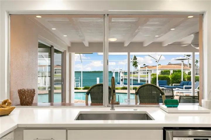 Kitchen featuring a water view, beam ceiling, white cabinetry, and sink