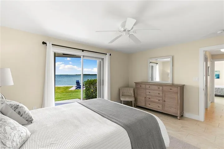 Bedroom featuring access to outside, light tile patterned floors, ceiling fan, and a water view