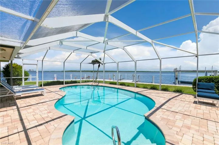 View of swimming pool featuring a lanai, a water view, and a patio area