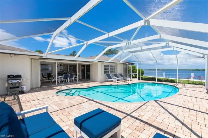 View of pool with a water view, a lanai, a patio, and a grill