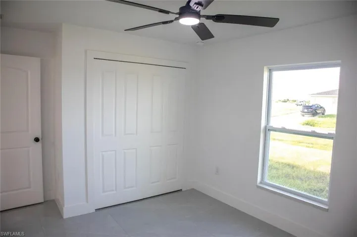 Unfurnished bedroom with light tile patterned flooring, ceiling fan, and a closet