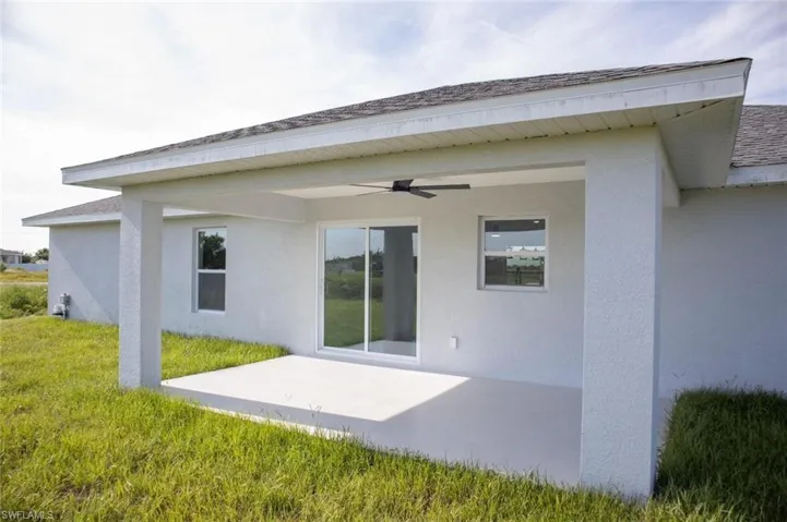Rear view of house featuring stucco siding, a patio, a ceiling fan, and a yard