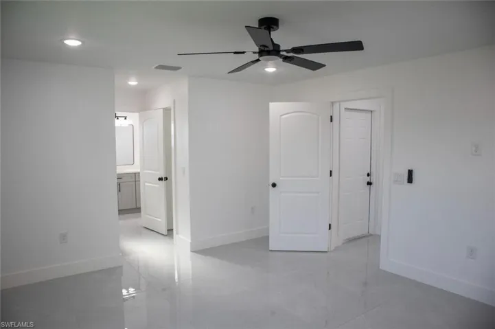 Unfurnished bedroom featuring recessed lighting, connected bathroom, ceiling fan, and light tile patterned flooring