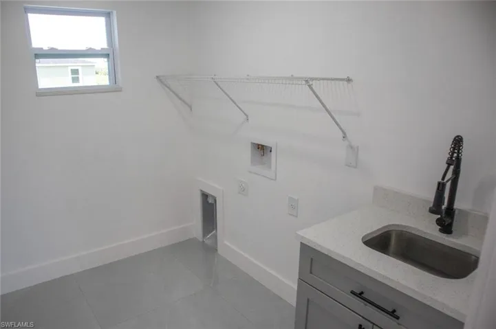 Laundry area featuring light tile patterned flooring, washer hookup, and cabinet space