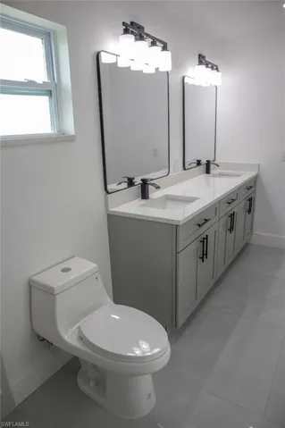 Bathroom with double vanity and light tile patterned floors