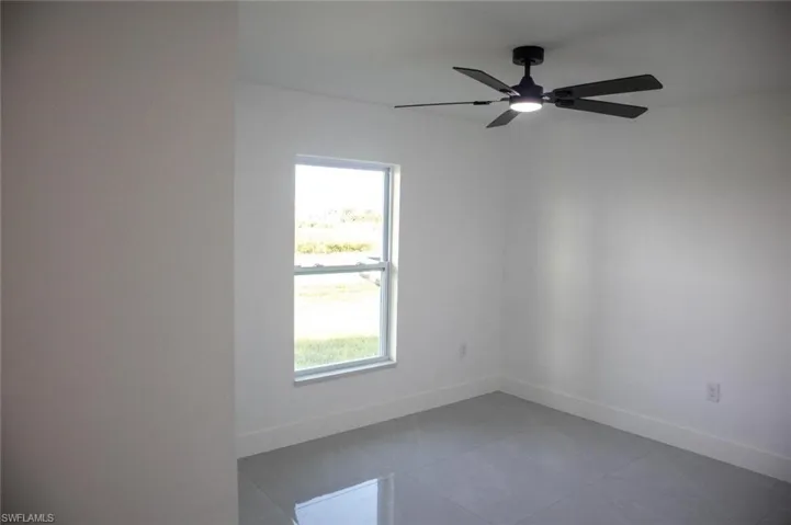 Empty room with light tile patterned floors and a ceiling fan