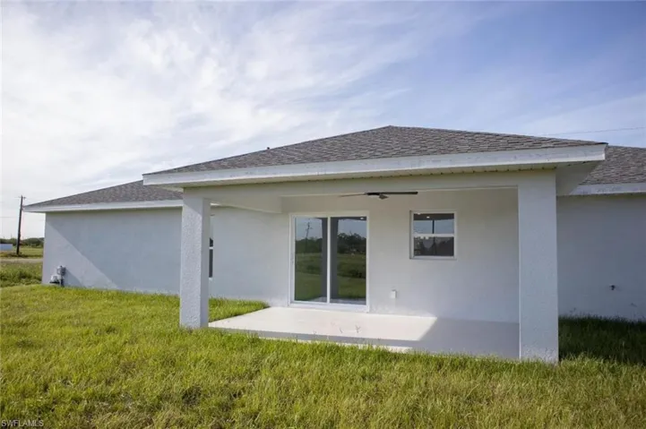 Back of house with a patio, stucco siding, and a yard
