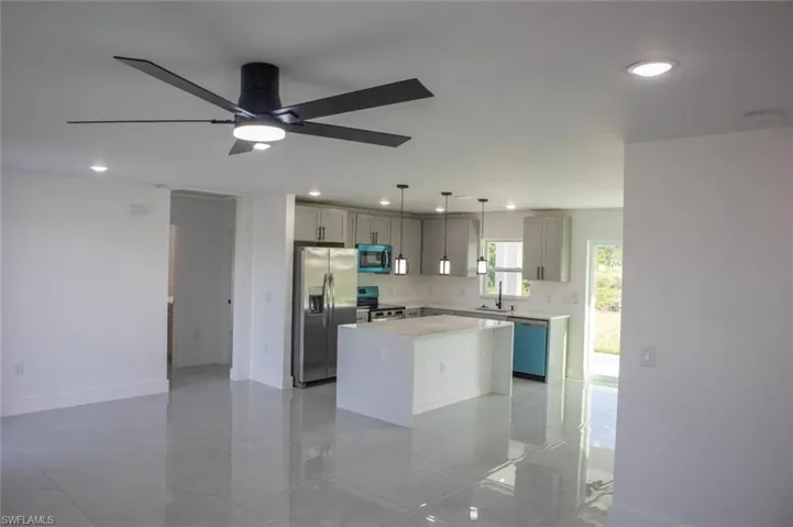 Kitchen with hanging light fixtures, stainless steel appliances, a center island, recessed lighting, and open floor plan