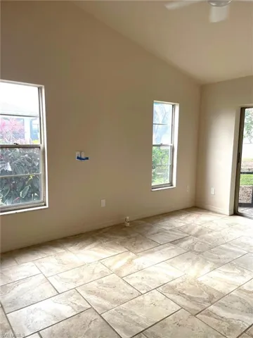 Spare room featuring ceiling fan, lofted ceiling, and a wealth of natural light