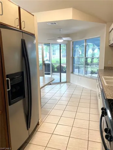 Kitchen featuring black range oven, ceiling fan, light tile patterned flooring, and stainless steel refrigerator with ice dispenser