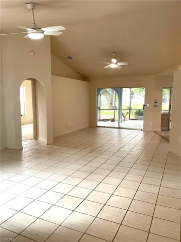 Empty room with lofted ceiling, ceiling fan, and light tile patterned floors