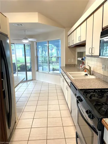 Kitchen featuring light tile patterned floors, stainless steel appliances, ceiling fan, and sink