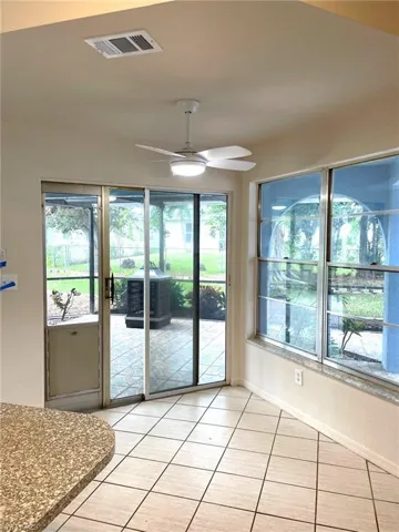 Doorway to outside with ceiling fan, a healthy amount of sunlight, and light tile patterned flooring