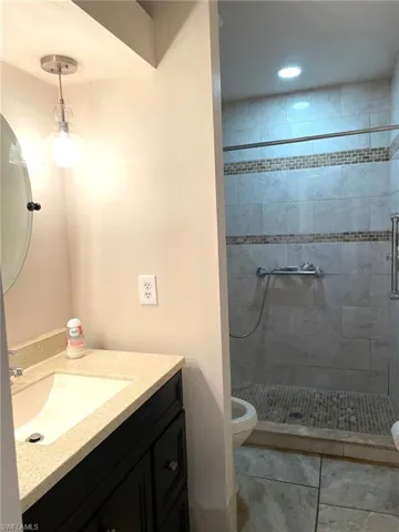 Bathroom featuring toilet, a shower with door, vanity, and tile patterned flooring