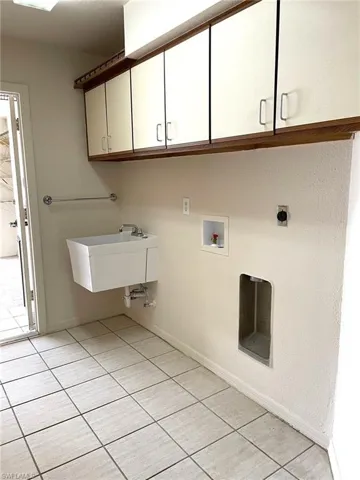 Washroom featuring sink, cabinets, electric dryer hookup, hookup for a washing machine, and light tile patterned floors
