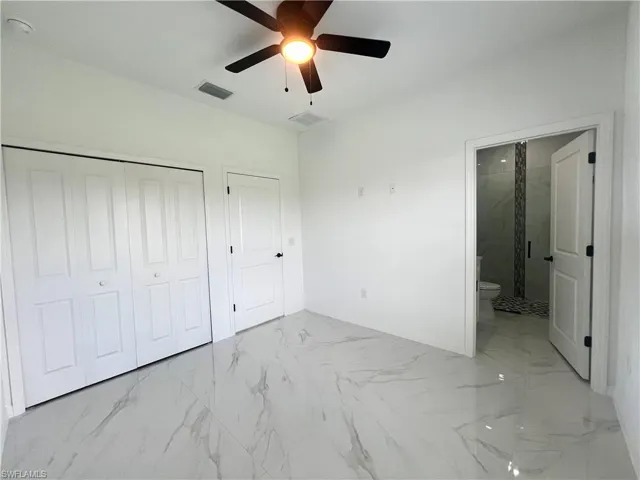 Unfurnished bedroom with marble finish floors, baseboards, connected bathroom, and a closet
