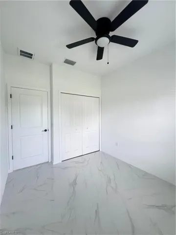 Unfurnished bedroom with a closet, marble finish floors, baseboards, and ceiling fan